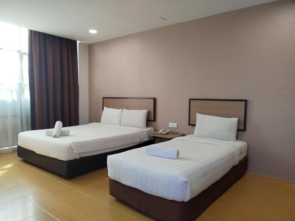a hotel room with two beds in a room at Maple Boutique Hotel Kota Bharu in Kota Bharu