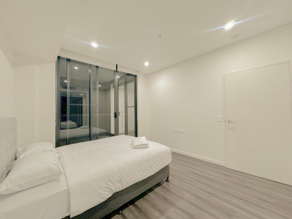 een witte slaapkamer met een bed en een grote spiegel bij Burwood Cozy Apartment Free Parking in Sydney