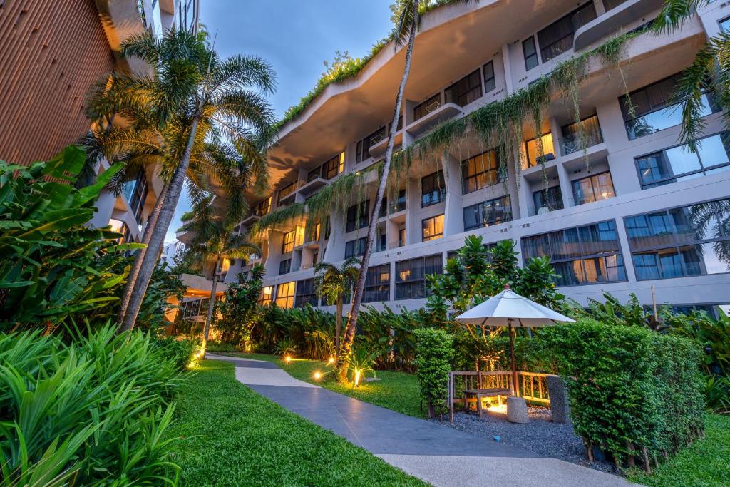 um edifício de apartamentos com um guarda-sol e um jardim em HOMA Phuket Town em Cidade Phuket