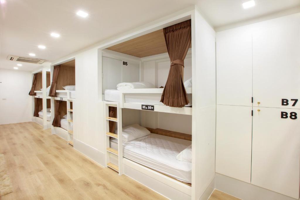 a room with white bunk beds in it at Lafami Hostel in Ban Nongdouang