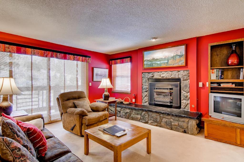 a living room with red walls and a fireplace at Tyra I A2D in Breckenridge