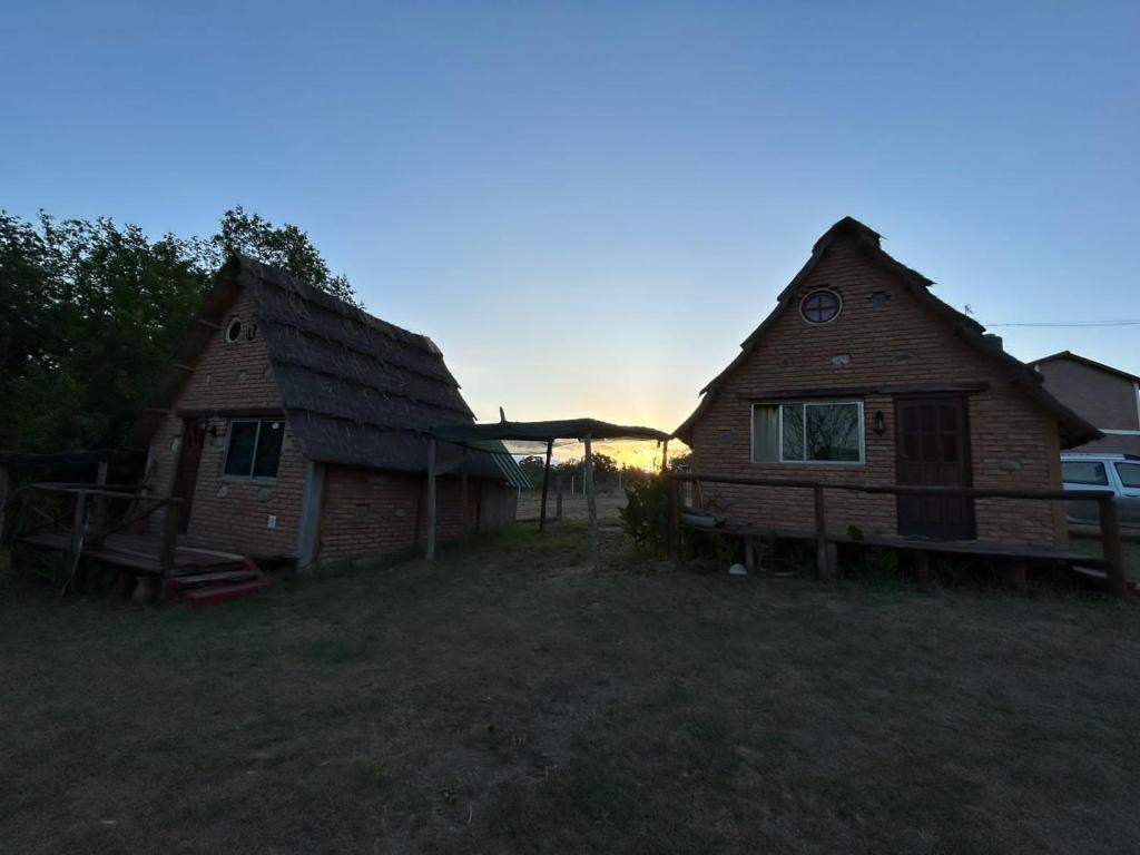 dos casas en un campo con la puesta de sol en el fondo en INTI naile en Villa Carlos Paz