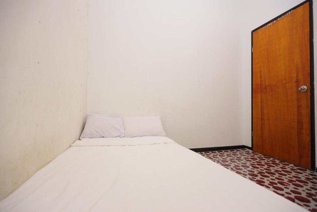 巴淡島中心的住宿－SPOT ON 93446 Penginapan Mak Yes，一间小卧室,配有一张床和一扇木门