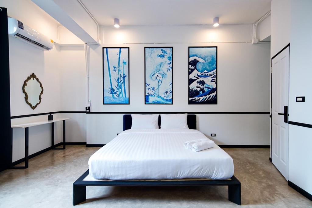 een slaapkamer met een bed en schilderijen aan de muur bij The Character Yaowarat เดอะ คาแรคเตอร์ เยาวราช in Samphanthawong