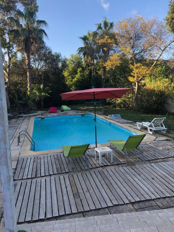 - une piscine avec 2 chaises et un parasol dans l'établissement LE BONHEUR AVEC PISCINE ET JARDIN, à Cassis