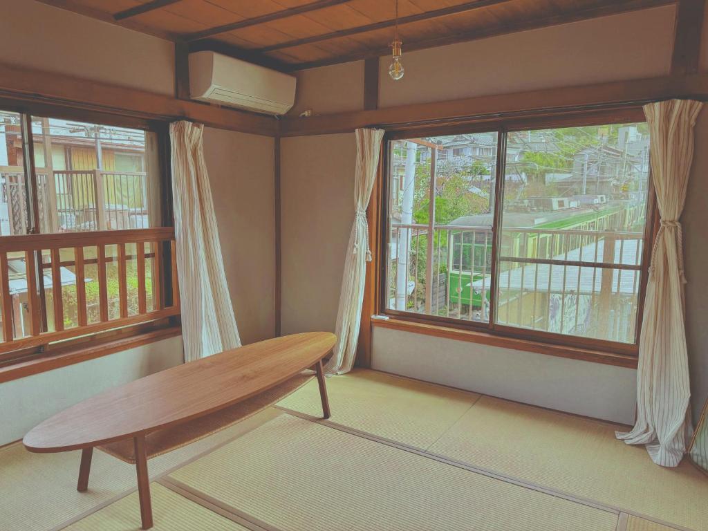 江ノ電の線路沿いにある宿【film koshigoe】 في كاماكورا: غرفة مع مقعد خشبي أمام نافذتين