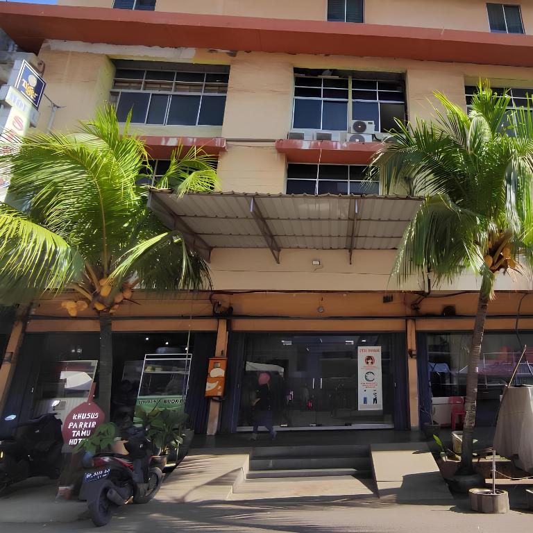 a building with palm trees in front of it at Hotel Sekawan in Jodoh