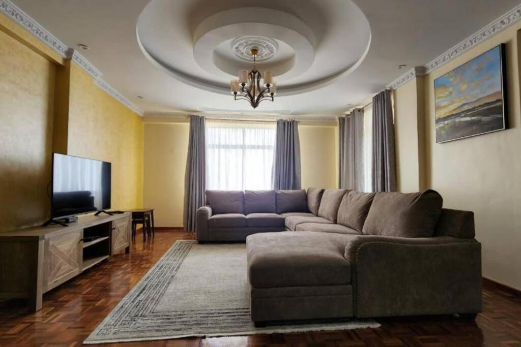 a living room with a couch and a television at Lovely Modern 2- bedroom apartment in Upperhill in Nairobi