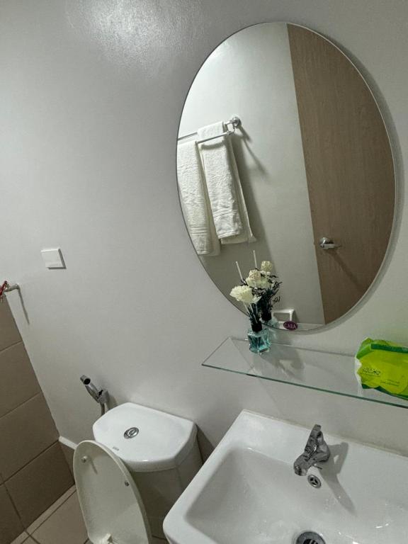 een badkamer met een wit toilet en een spiegel bij Condotel - Minimalistic 2 minutes walk to SM Marilao in Marilao