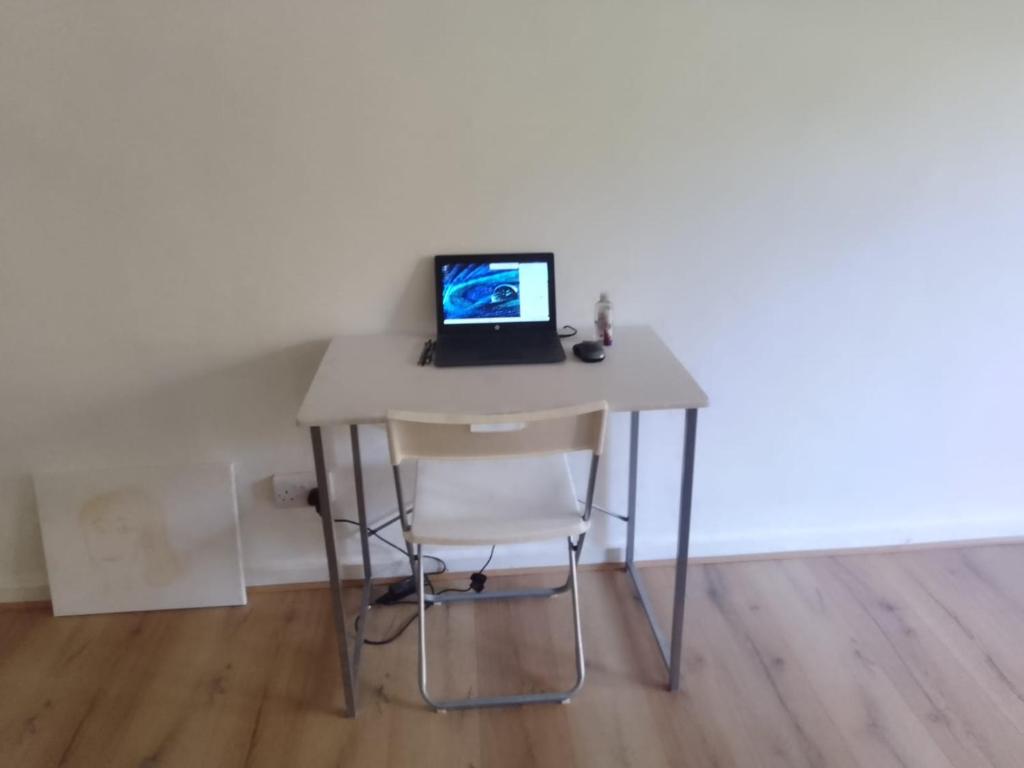um computador portátil sentado numa secretária com uma cadeira em Lodgings. em Londres