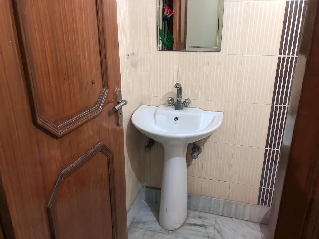 a bathroom with a sink and a mirror and a door at Shastreey Sangeet Nivas in Vrindāvan