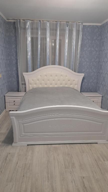 a white bed in a bedroom with blue walls at Двухкомнатная в 4 микрорайоне in Oral