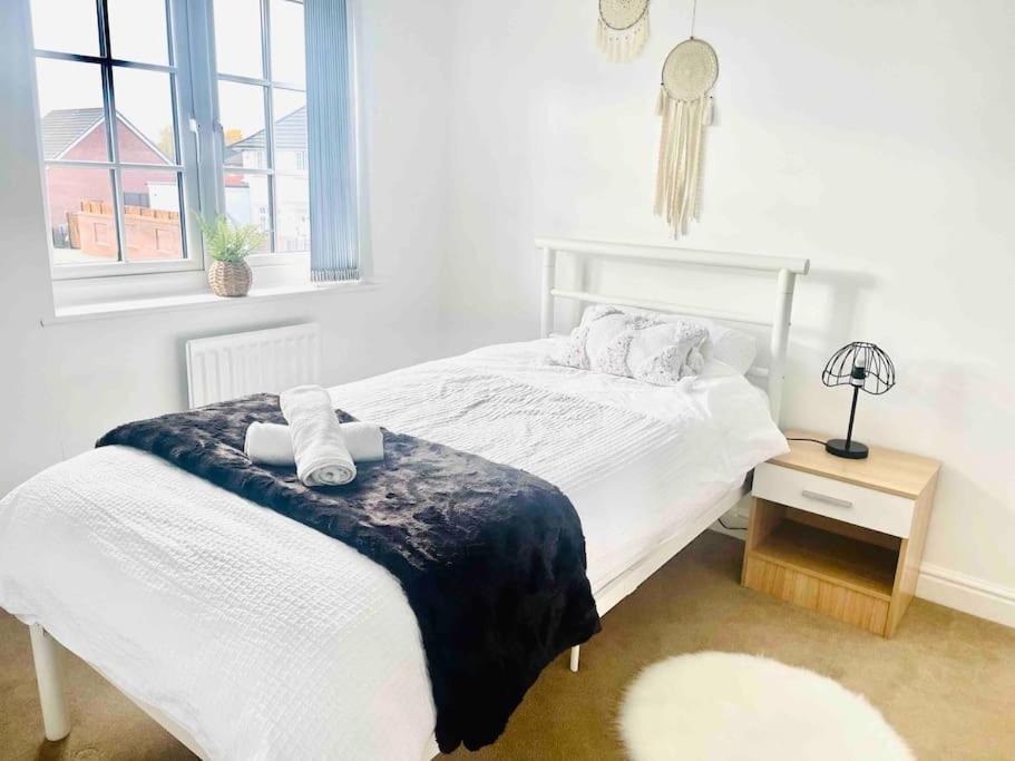 1 cama blanca en un dormitorio con ventana en Modern 4 bed house perfect for contractors with free parking, en Mánchester