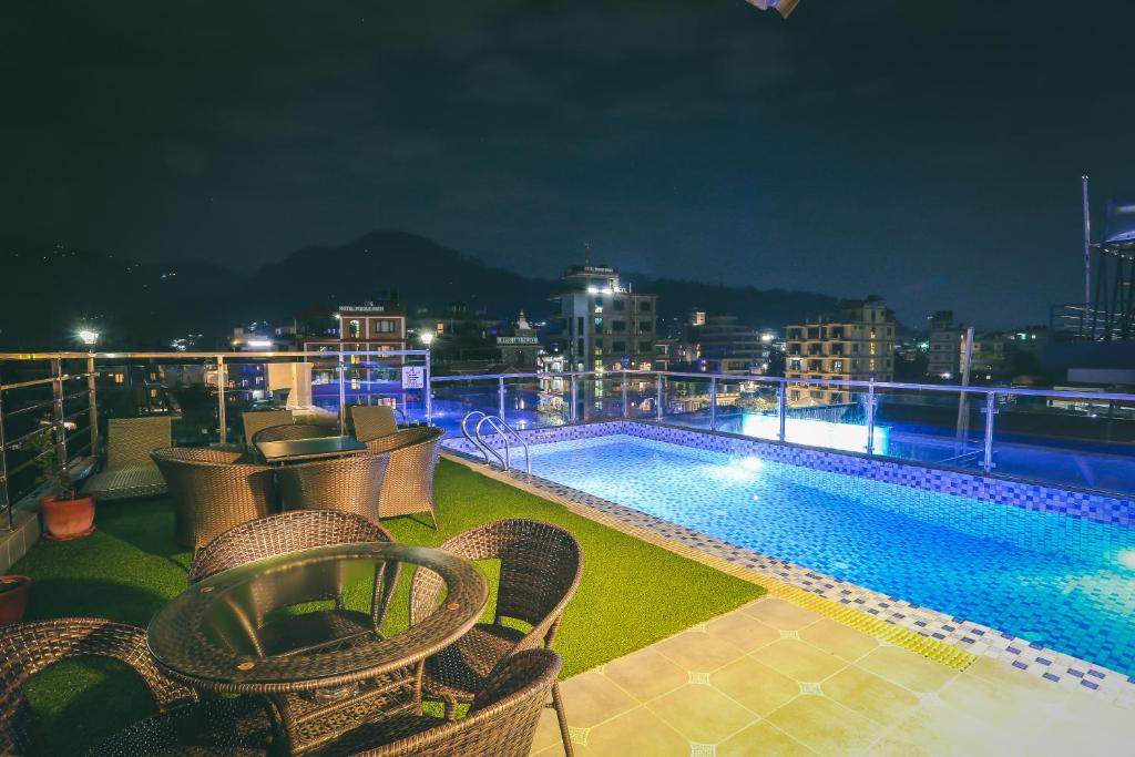 a balcony with chairs and a swimming pool at night at Hotel Eco Tree Pokhara in Pokhara
