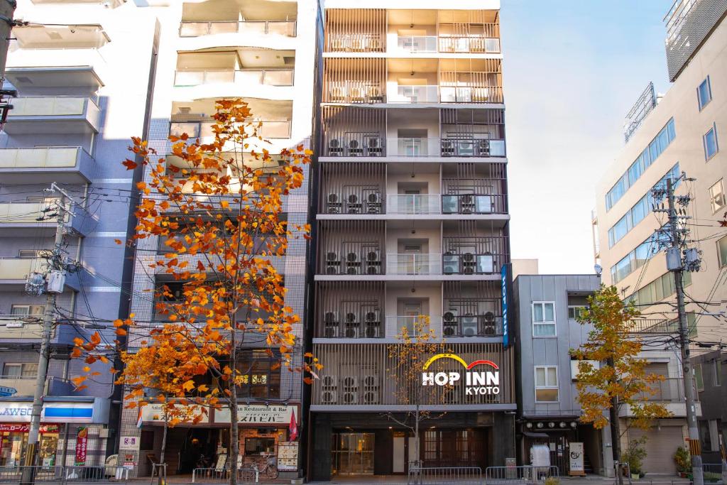a tall building with a tree in front of it at Hop Inn Kyoto Shijo Omiya in Kyoto