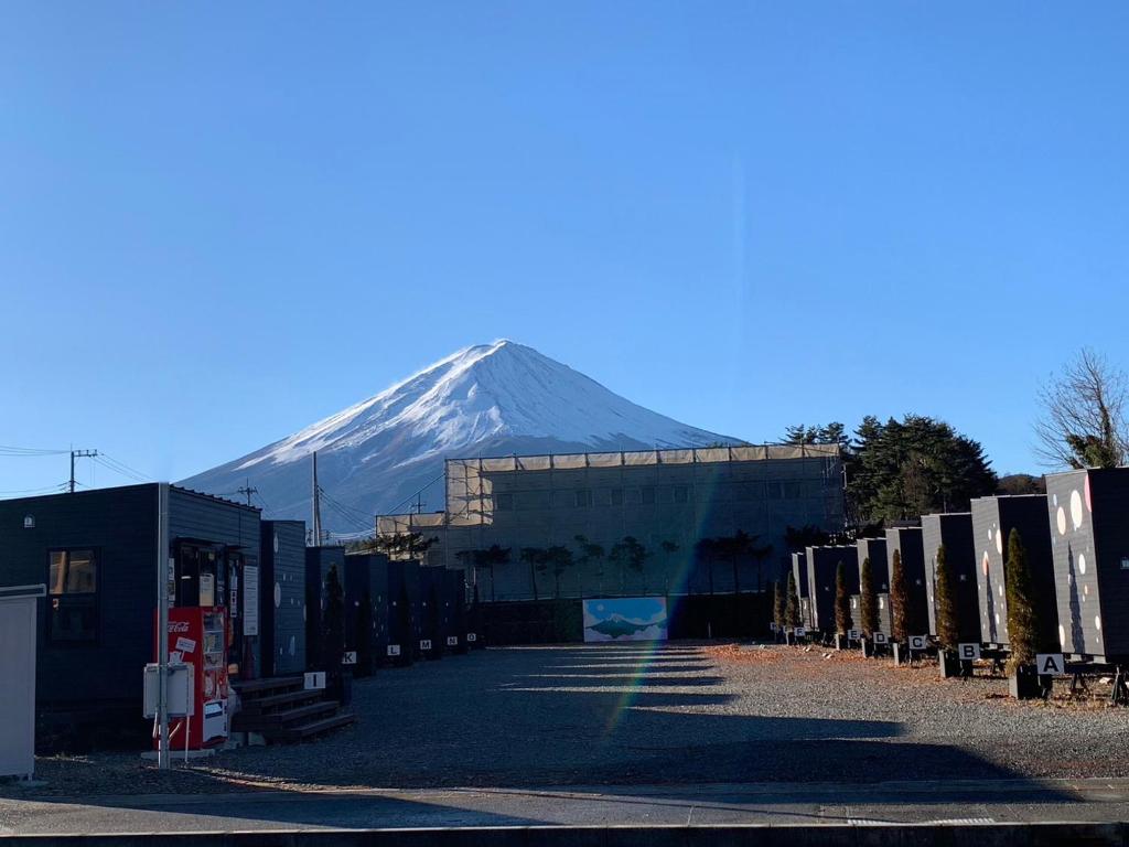 a snow covered mountain in the distance behind a building at Mt Fuji Glamping VILLA Kawaguchiko in Fujikawaguchiko