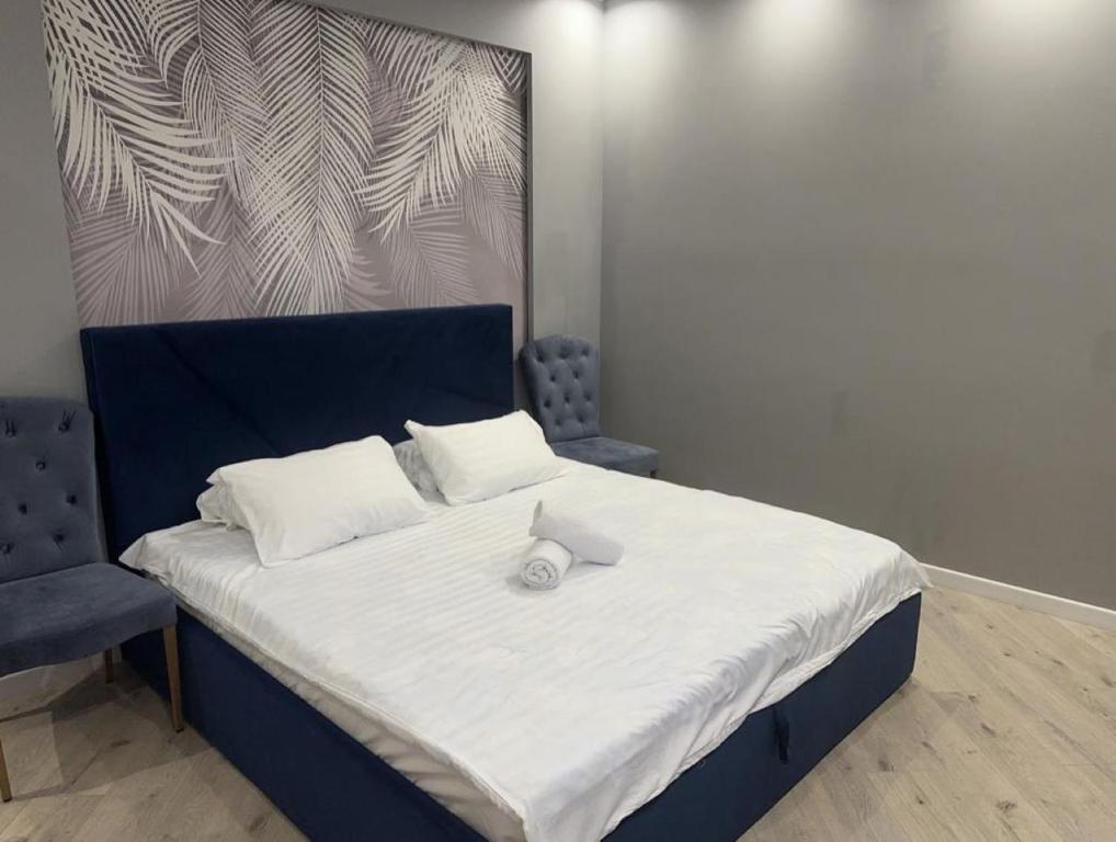 een slaapkamer met een bed met een blauw hoofdeinde bij ЖК Falcon City in Alma-Ata