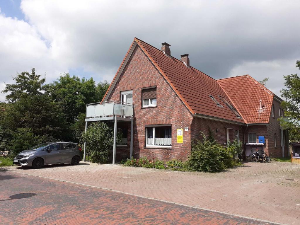 una casa de ladrillo con un coche aparcado delante de ella en Balkonwohnung Norderney, en Hooksiel