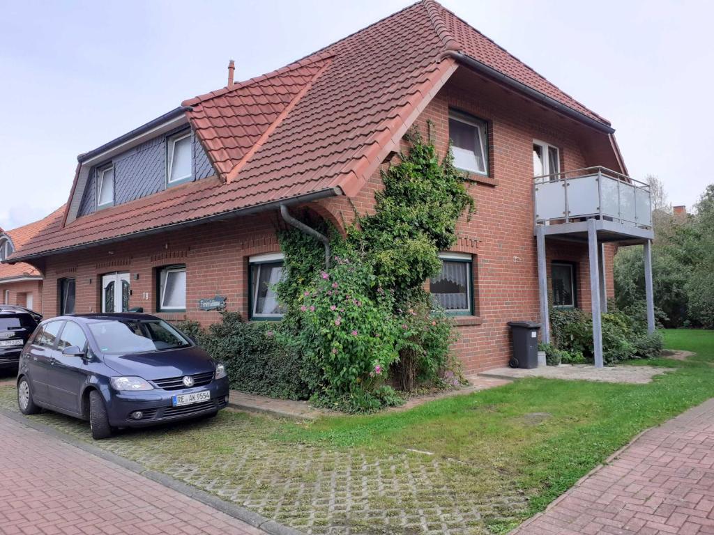 a house with a car parked in front of it at Balkonwohnung Leuchtturm in Hooksiel