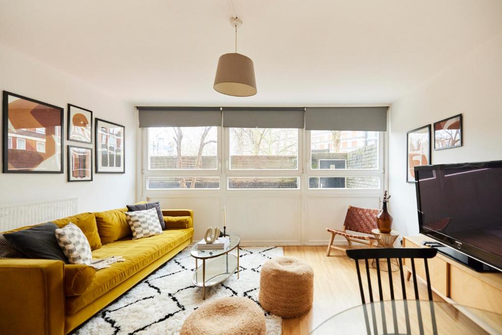 a living room with a yellow couch and a tv at The Kennington Park Crib - Lovely 2BDR Flat with Garden in London