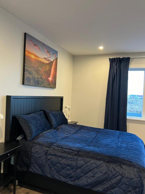 a bedroom with a blue bed and a window at Nyibaer studio apartment in Selfoss