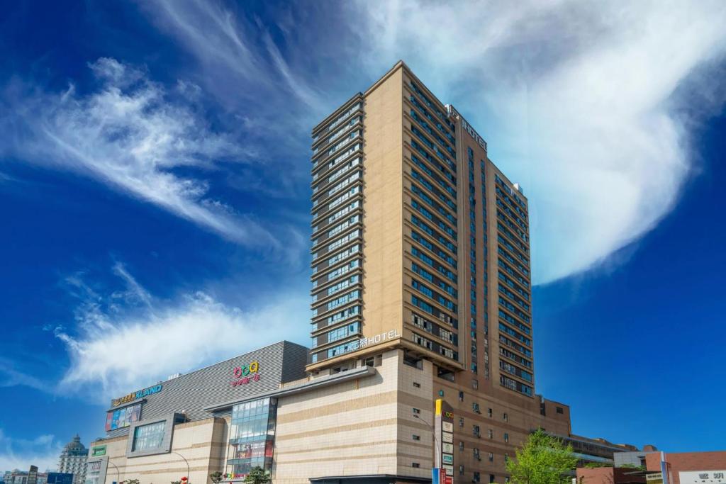 a tall building in front of a blue sky at Yunmu Hotel Luzhou in Luzhou