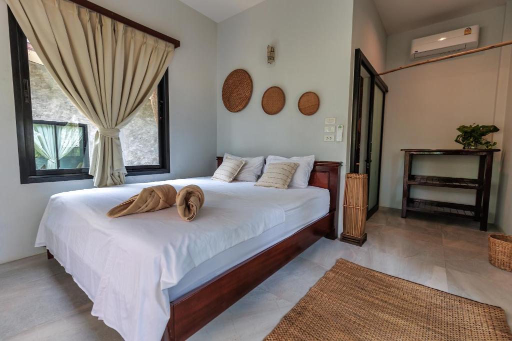 a bedroom with a large white bed with two towels on it at Why Nam Beach in Haad Yuan