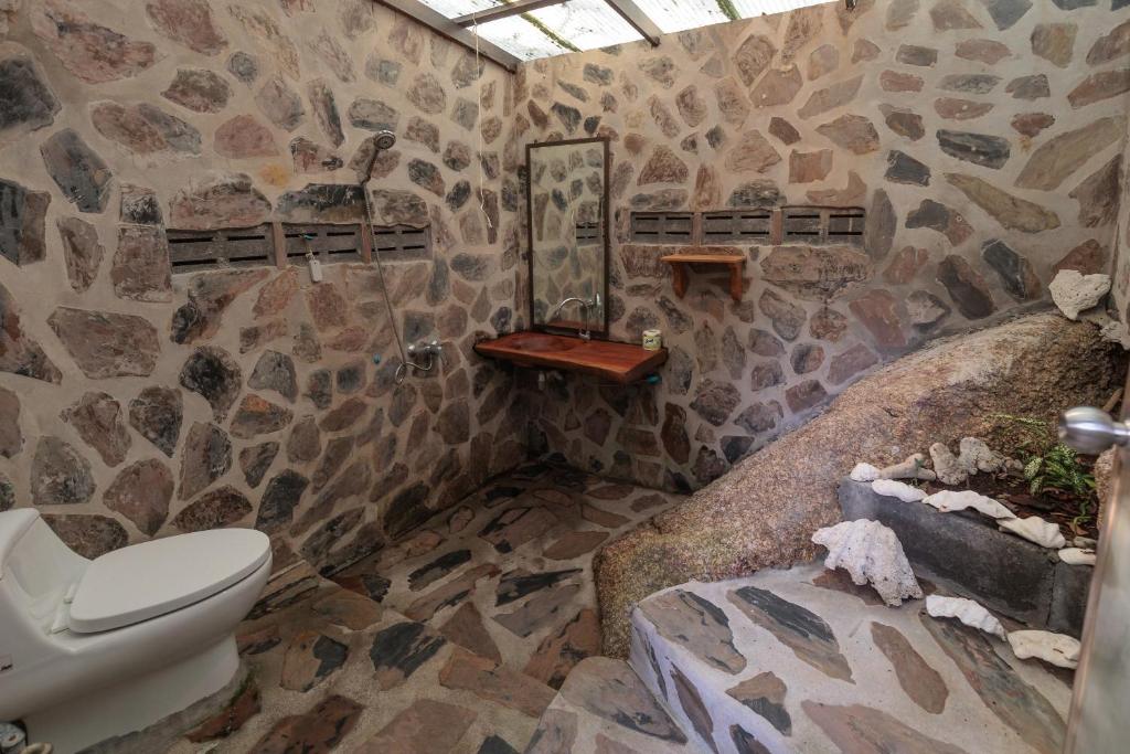 a stone bathroom with a toilet and a sink at Why Nam Beach in Haad Yuan
