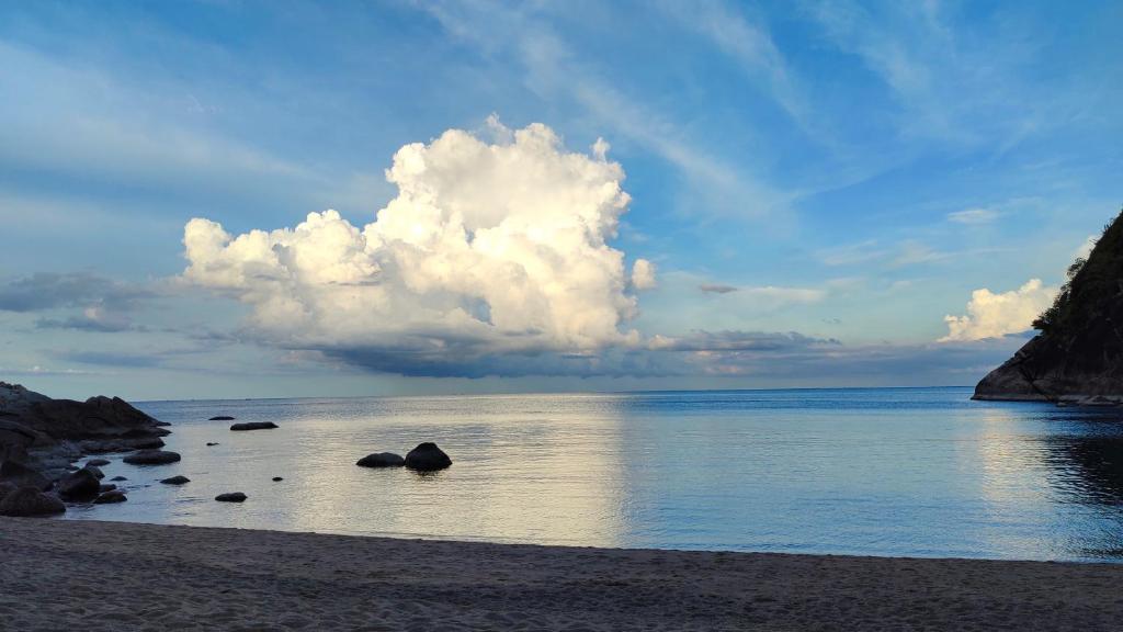 a cloud over a beach with rocks in the water at Why Nam Beach in Haad Yuan