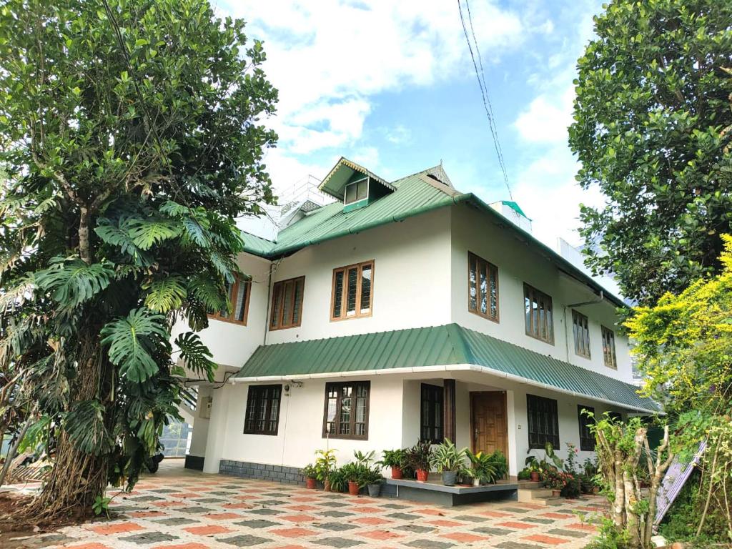 a large white house with a green roof at Tea & Sky Munnar in Munnar