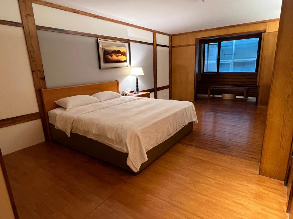 1 dormitorio con 1 cama grande y suelo de madera en King's Resort & Spa en Taian