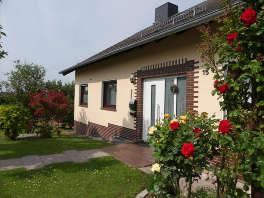 une maison avec des roses rouges devant elle dans l'établissement Ferienwohnung Sigrun, à Niedenstein