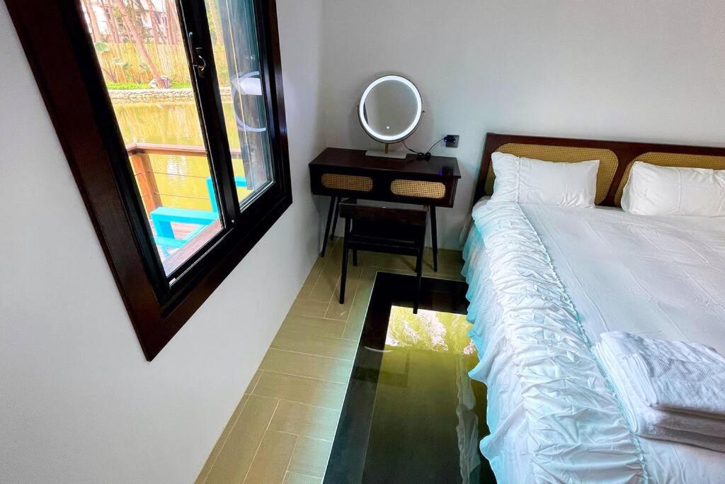 1 dormitorio con cama y espejo junto a una ventana en Wooden House on lake,city center, en Luang Prabang