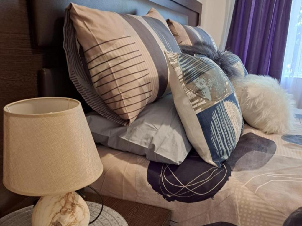 una pila de almohadas en una cama con lámpara en Kettle Guest Lodge Rustenburg, en Rustenburg