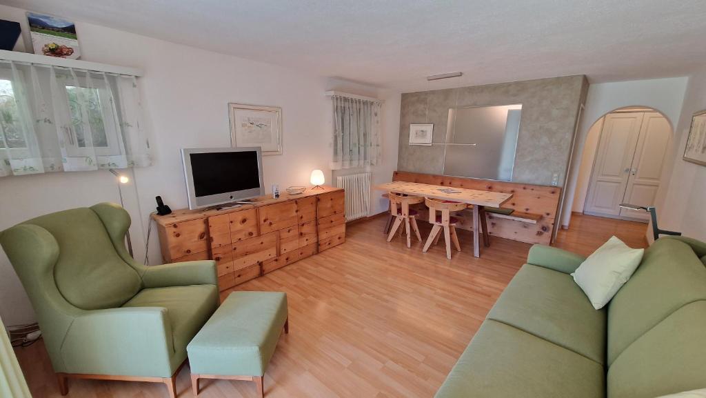 een woonkamer met een bank, een televisie en een tafel bij Chesa Bellaval, Haus Leivra 2-Zimmerwohnung in Silvaplana
