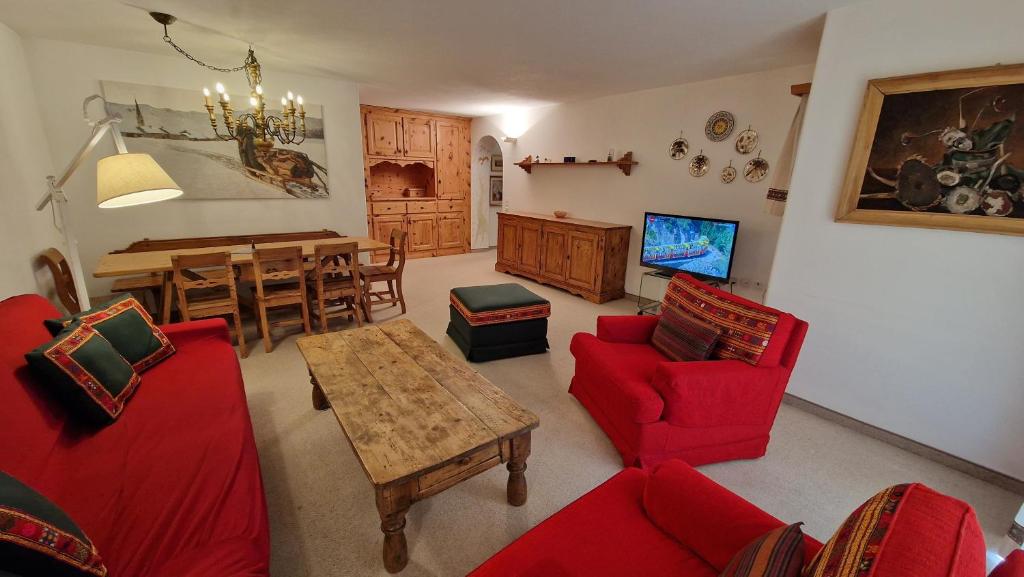 sala de estar con muebles de color rojo y comedor en Chesa Bellaval, Haus Chamuotsch 3 1 2-Zimmerwohnung, en Silvaplana
