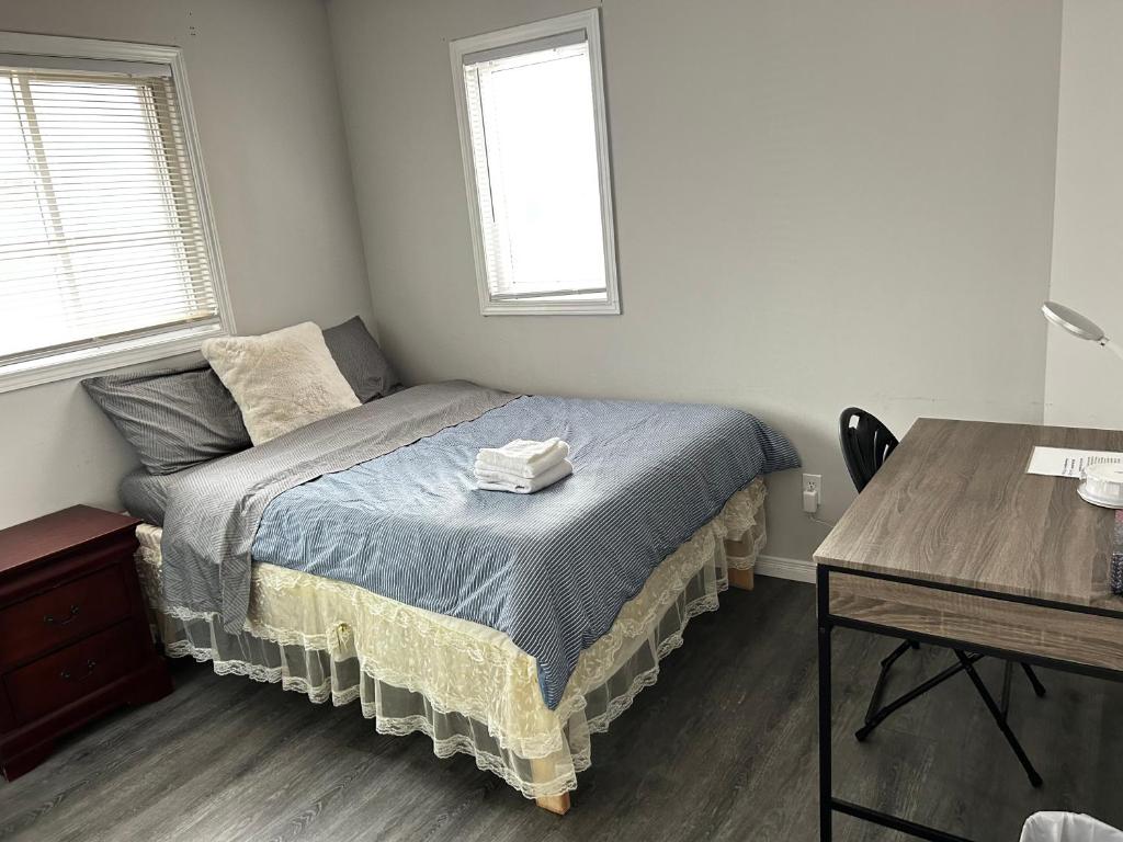 a bedroom with a bed and a desk and two windows at Comfortable room B in Kitchener