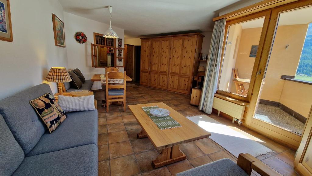シルヴァプラーナにあるChesa Bellaval, Haus Rizza 1 1 2-Zimmerwohnungの青いソファとテーブルのあるリビングルーム
