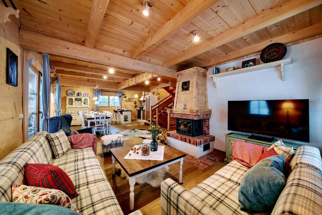 una sala de estar con sofás y chimenea en una casa en Marusina Chalets, en Szaflary