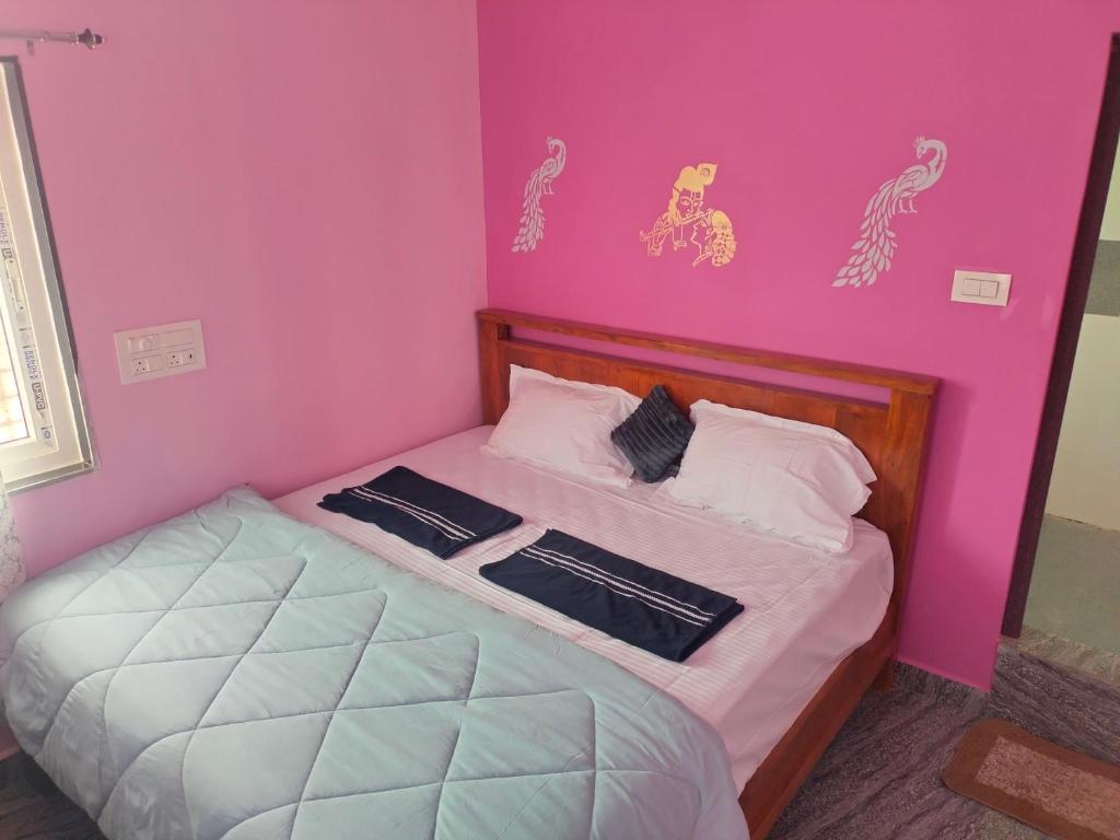 a small bedroom with a bed with a pink wall at Supritha Homestay Hampi in Hampi