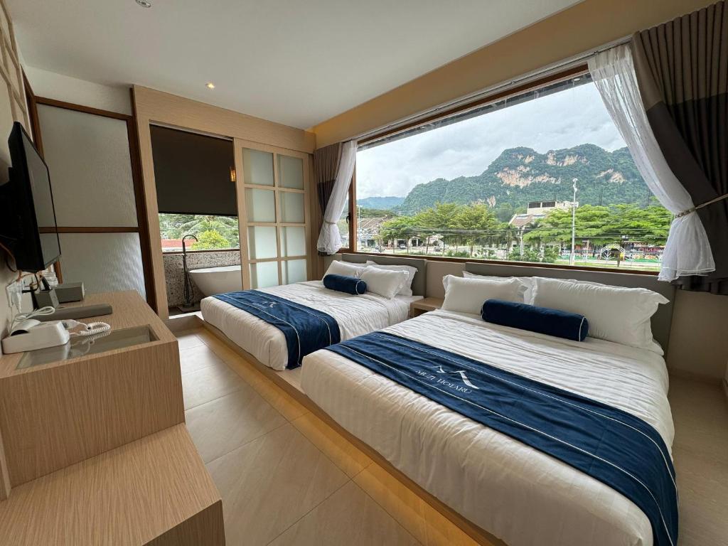 a hotel room with two beds and a large window at Muzi Boutique Hotel in Ipoh