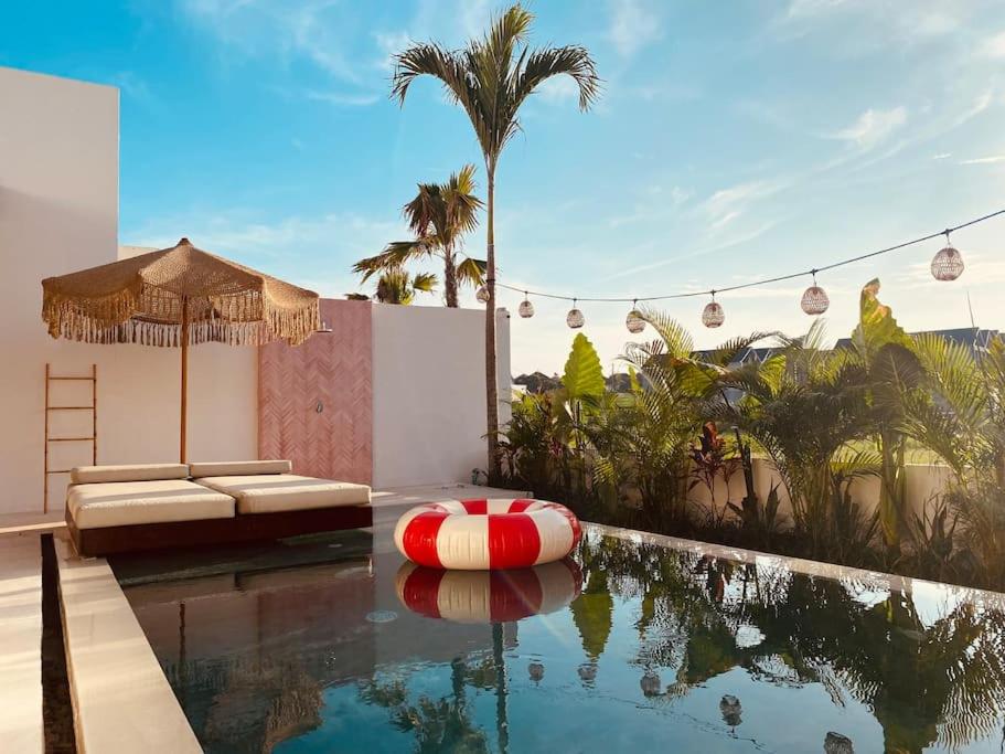 uma piscina com uma jangada vermelha e branca na água em VILLA ROSADO - Canggu's Hidden Gem: beautiful boutique Villa em Canggu