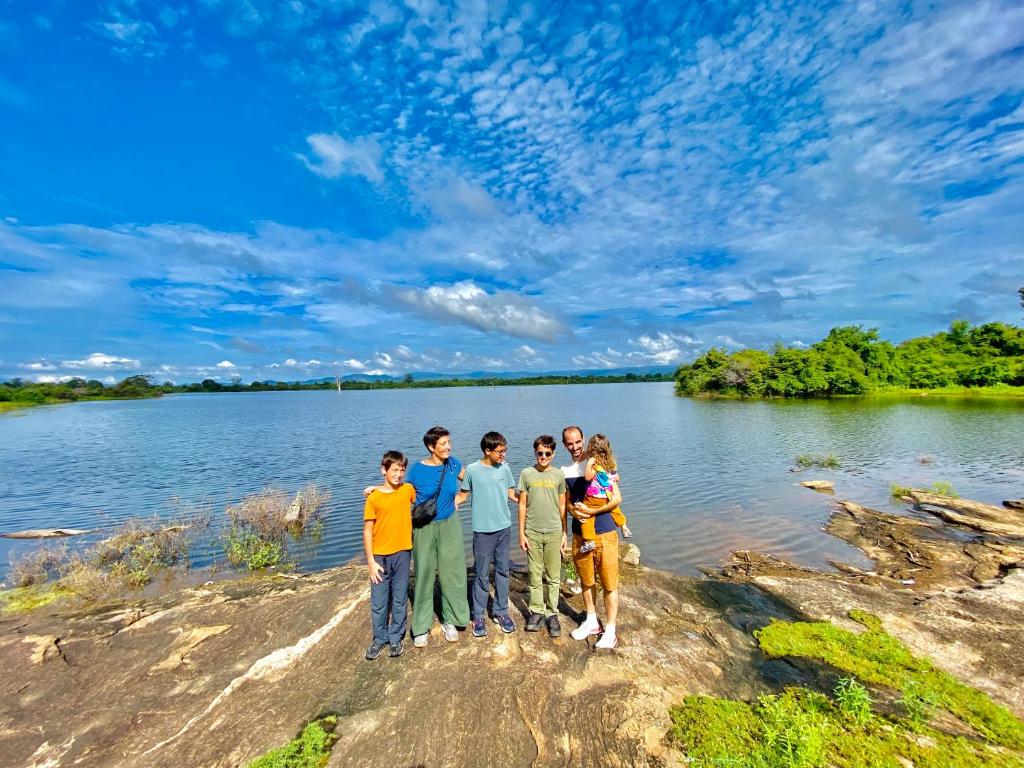 un grupo de personas de pie en la orilla de un lago en Pearl White House en Udawalawe