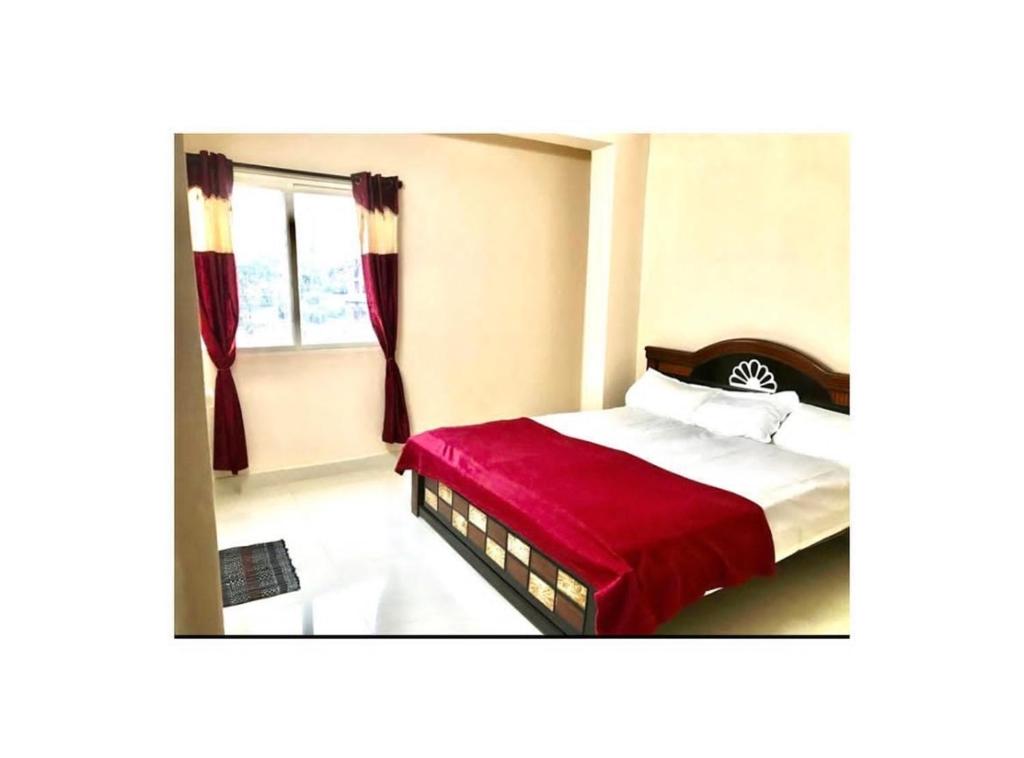a bedroom with a bed with a red blanket and a window at Reef Hotel in Shamshabad