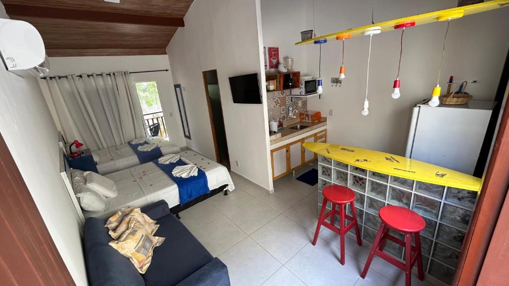 1 dormitorio pequeño con 1 cama y 2 taburetes rojos en Flat temático Solar Água, en Pipa