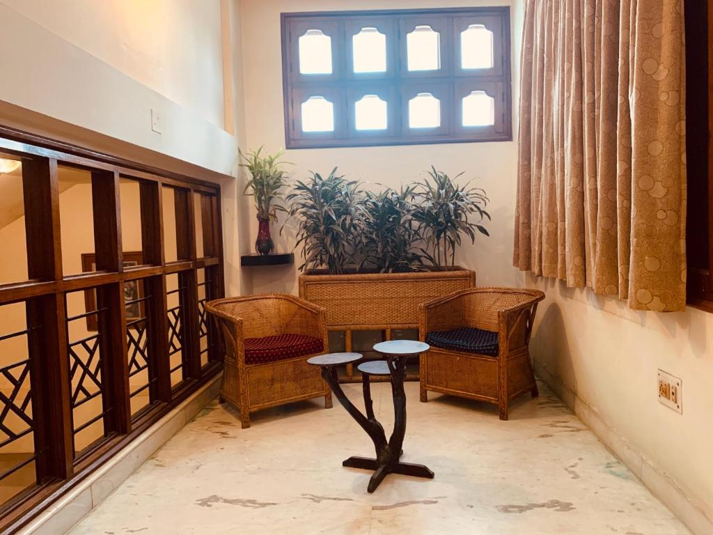 a room with chairs and a table and a window at Hotel Devika in Dibrugarh