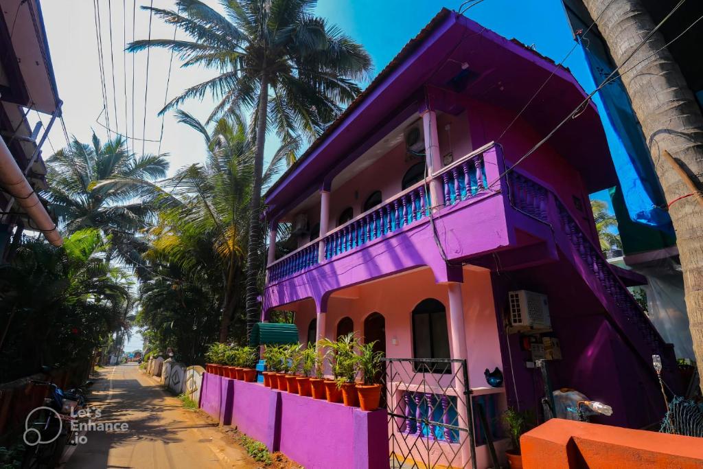 a pink house on a street with palm trees at Ocean View Cottage in Calangute