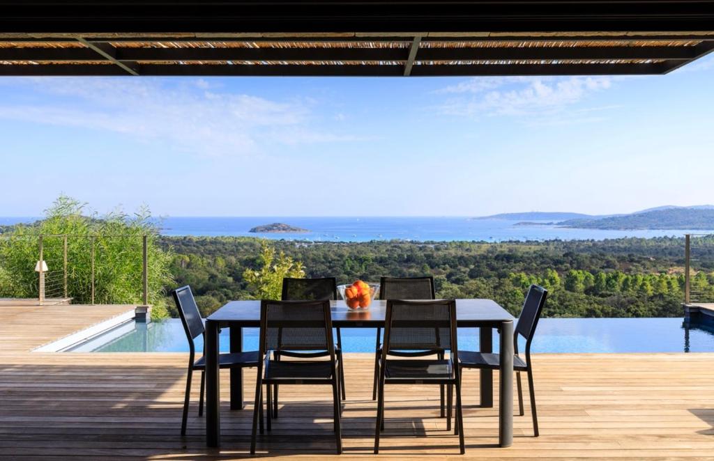 a dining table and chairs on a deck with a view at Villa Nepita in Lecci