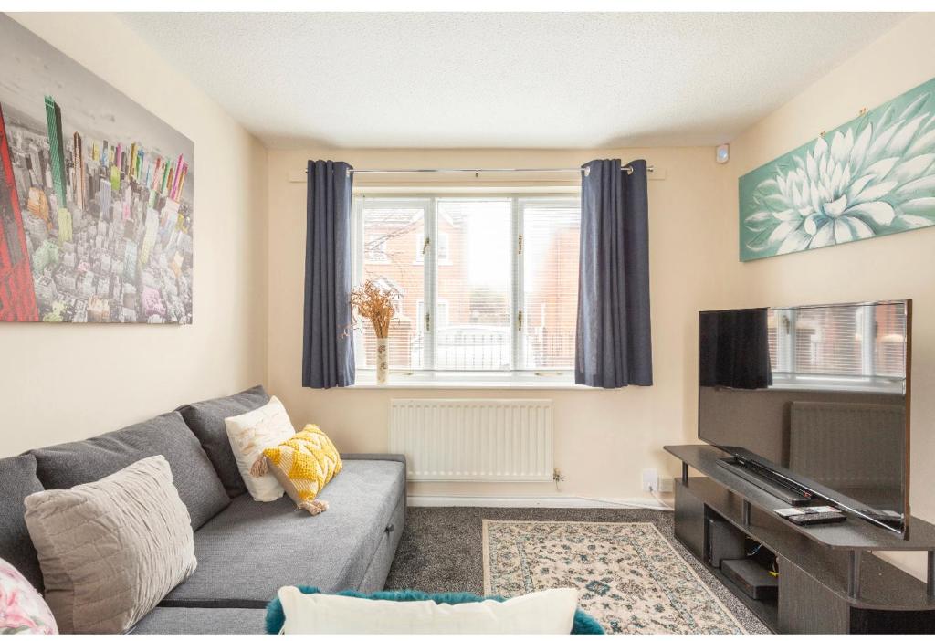 ein Wohnzimmer mit einem Sofa und einem TV in der Unterkunft New Manchester Getaway Home - Free Parking in Manchester