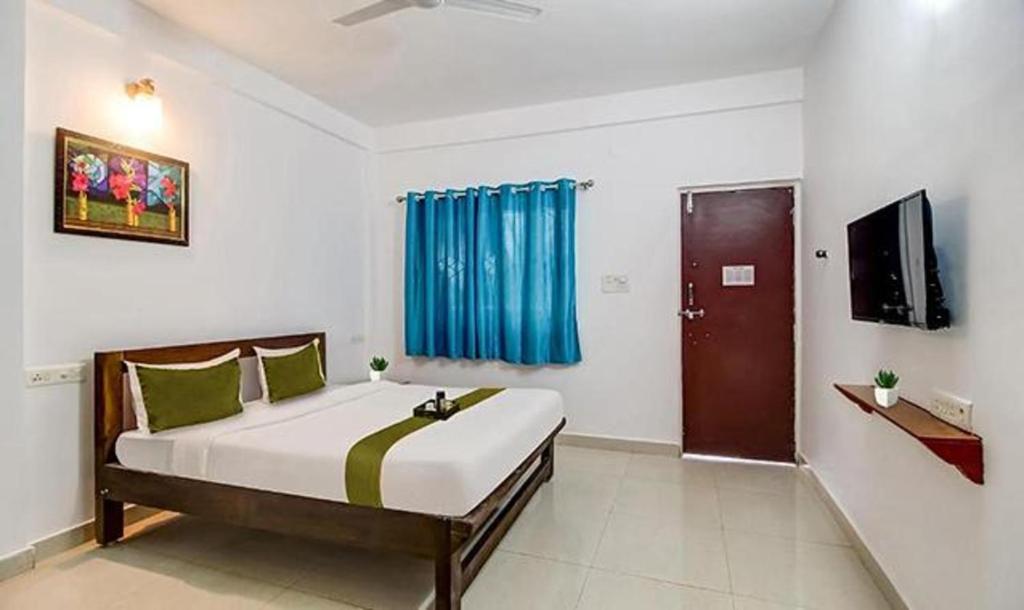 a bedroom with a large bed with a blue curtain at FabExpress Aqua Vista in Morjim